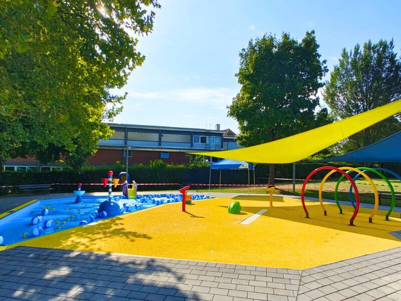 Das Planschbecken im Freibad Waiblingen mit blauem Kinderbecken links und gelben Spraypark rechts.