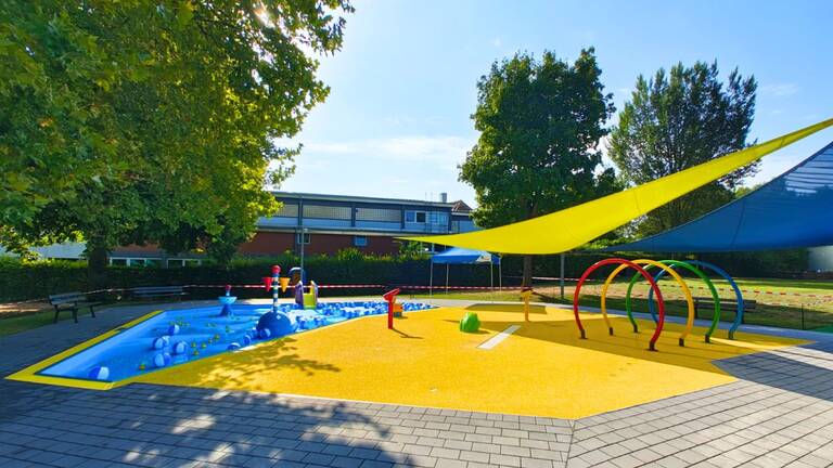 Das Planschbecken im Freibad Waiblingen mit blauem Kinderbecken links und gelben Spraypark rechts.