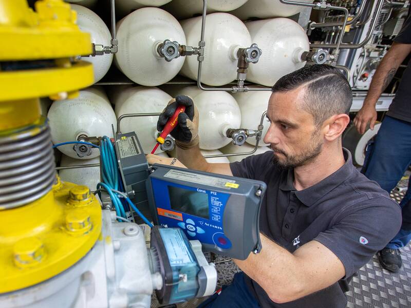 Ein Stadtwerke Waiblingen-Mitarbeiter der mit einem Schraubenzieher und einem Prüfgerät eine Gasanlage prüft. Links am Bildrand sieht man ein großes gelbes Gasrohr.