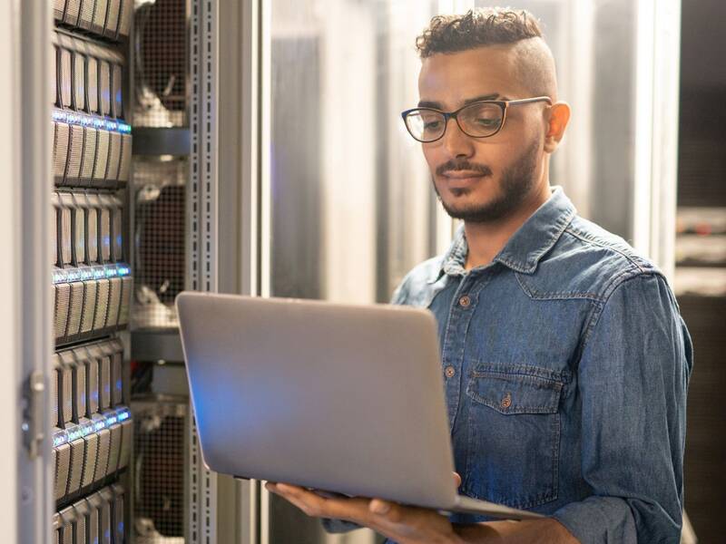 Junger Mann mit Laptop am Rechenzentrum