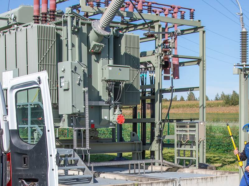 Zwei Stadtwerke Mitarbeiter am Kastenwagen vor einem Umspannwerk