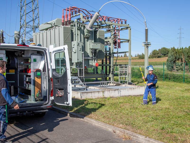 Zwei Stadtwerke Waiblingen Monteure vor einem Stadnwerke Auto neben einem Umspannwerk